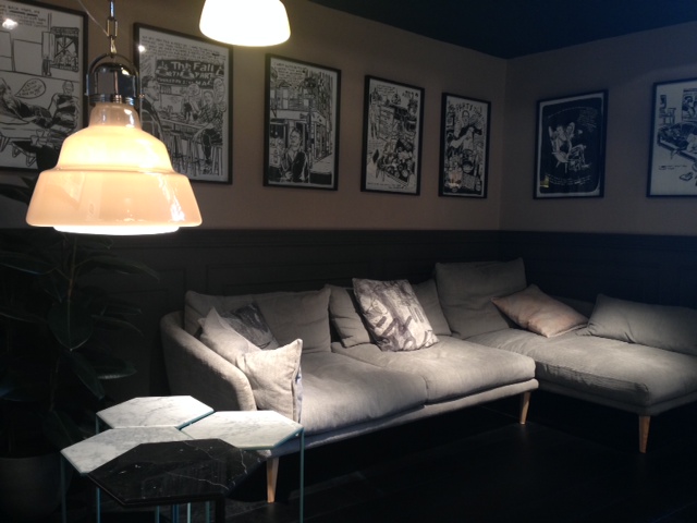 Ambiente do iSaloni 2014 com seqüência de quadros em preto e branco sobre parede bicolor, luminárias Foscarini e sofá ultra confortável da Moroso.