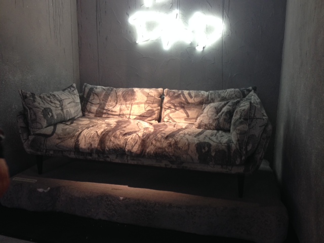 Em todas as vitrines Diesel está o sofá Nebula Nine com tecido em estampa tie die com tons de cinza e o letreiro em néon que diz